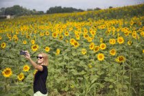 Frau macht Selfie gegen Sonnenblumenfeld — Stockfoto