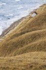 Мальовничий вид на будинок на пагорбі з морськими хвилями на фоні — стокове фото