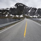 Vue de la route menant sur le lac à la chaîne de montagnes — Photo de stock