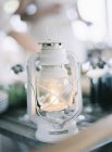 Lit up small white lantern on table — Stock Photo