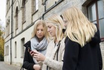 Jovens mulheres atraentes verificando smartphone no campus universitário — Fotografia de Stock