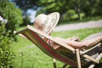 Seitenansicht einer Seniorin, die es sich auf einem Sonnenstuhl bequem macht — Stockfoto