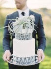 Жених держит свадебный торт, сосредоточиться на переднем плане — стоковое фото