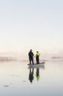 Молодые люди рыбачат в озере на закате — стоковое фото