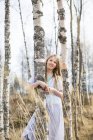 Menina sorridente em pé junto a bétula na floresta — Fotografia de Stock