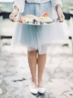 Mulher em saia elegante segurando bandeja de prata com sobremesas, tiro cortado — Fotografia de Stock