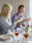 Улыбающиеся мужчина и женщина поднимают бокалы с вином в праздничных тостах — стоковое фото