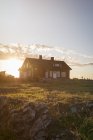Дерев'яний будинок на зеленому пагорбі на заході сонця — стокове фото