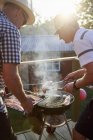 Two men grilling fish, focus on foreground — Stock Photo
