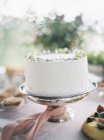 Torta bianca su supporto torta con nastro rosa — Foto stock