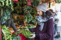 Woman choosing christmas wreath at market — Stock Photo