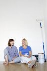 Young women resting by wall after home renovation work — Stock Photo