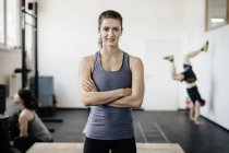 Portrait de jeune femme debout dans la salle de gym avec les bras croisés — Photo de stock
