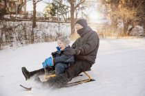 Father with son tobogganing, focus on foreground — Stock Photo