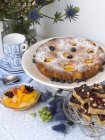 Peach cake with blueberries served with other desserts on table — Stock Photo