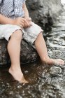 Дитячий хлопчик занурює ноги у воду, вибірковий фокус — стокове фото