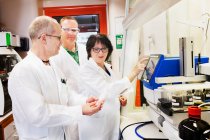 Чоловічі та жіночі вчені в білих пальто, що працюють в лабораторії — стокове фото