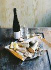 Smoked fish, lemon, cutlery and bottle of wine on wooden table — Stock Photo