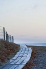 Wooden boardwalk leading to beach at dusk — Stock Photo