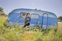 Teenage girl in front of travel trailer in grass — Stock Photo