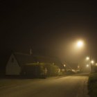 Strada nebbiosa e strada illuminata di notte — Foto stock