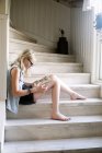 Girl reading book on wooden steps at home — Stock Photo