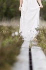Menina adolescente em vestido branco em pé no viaduto no prado — Fotografia de Stock