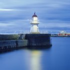 Long plan d'exposition du phare illuminé la nuit — Photo de stock