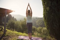 Femme pratiquant le yoga contre les collines vertes — Photo de stock
