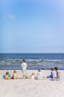 Vue arrière de deux femmes avec enfants sur la plage — Photo de stock