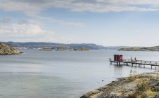 Bay of water with people on pier and distant mountains — Stock Photo