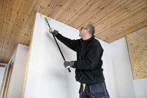 Homme mûr peinture mur à la maison — Photo de stock