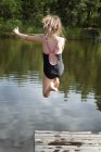 Teenage girl jumping in river water — Stock Photo