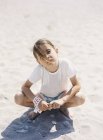 Menina sentada na praia de areia, foco seletivo — Fotografia de Stock