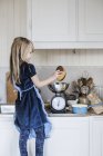 Little girl with blonde hair cooking at kitchen — Stock Photo