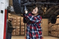Female mechanic adjusting wheel indoors — Stock Photo