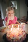 Дівчина з світлим волоссям дивиться на торт на день народження — стокове фото