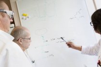 Scientists writing chemical formulas on whiteboard, selective focus — Stock Photo