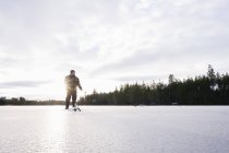 Homem se preparando para a pesca no gelo no lago congelado — Fotografia de Stock