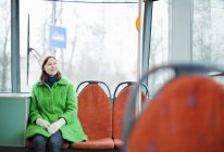 Mujer joven sentada en tranvía y sonriendo - foto de stock