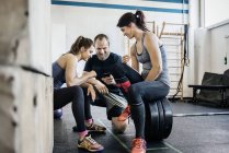 Young women and man using phone at gym — Stock Photo