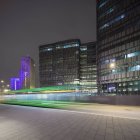 Light trails and city buildings illuminated at night — Stock Photo