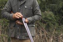 Средняя часть человека заряжает пистолет в лесу — стоковое фото