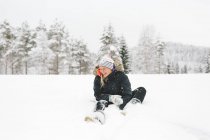 Laughing young woman sitting in snow — Stock Photo