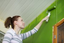 Low angle view of mid-adult woman painting room — Stock Photo