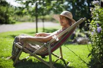 Senior woman relaxing on sun chair — Stock Photo