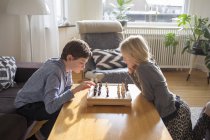 Boy and girl playing chess in living room — Stock Photo