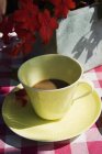 Nahaufnahme von Kaffee in gelber Tasse und roten Blumen — Stockfoto