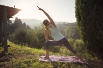 Mujer practicando yoga contra verdes colinas - foto de stock