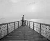 Immagine in bianco e nero dell'uomo che guarda la vista sul molo — Foto stock